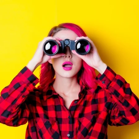 Woman with pink hair looking through binoculars